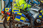 Two London Metropolitan police officers in high-vis jackets sat on parked motorcycles.