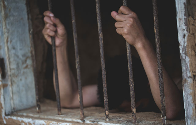 A person stuck behind prison bars