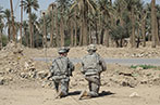 Two soldiers kneeling on the side of the road in Iraq.