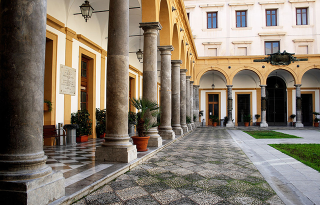 The main patio of the University of Palermo with marble columns and lawns.