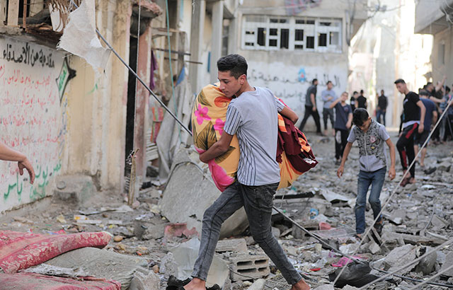 A young man walking amongst rubble in Gaza, Palestine.