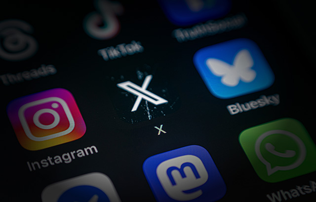 A close up of a phone screen with the Instagram, X, and BlueSky logos displayed.