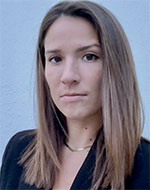 Amanda Brown. She has long brown hair and is wearing a black jacket and a gold necklace.