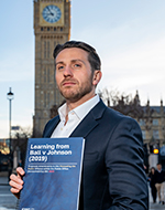 Marcus J. Ball standing by Big Ben with a draft of the Hillsborough Law.