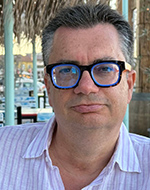 Dr Joan Barata. He is wearing thick rimmed glasses and a light purple stiped shirt.