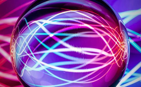 A metallic orb reflecting strings of blue and purple light.