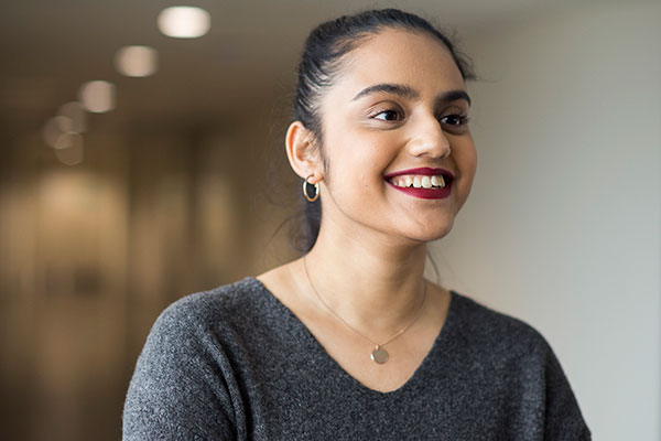A Queen Mary LLB Student stood in a corridor smiling