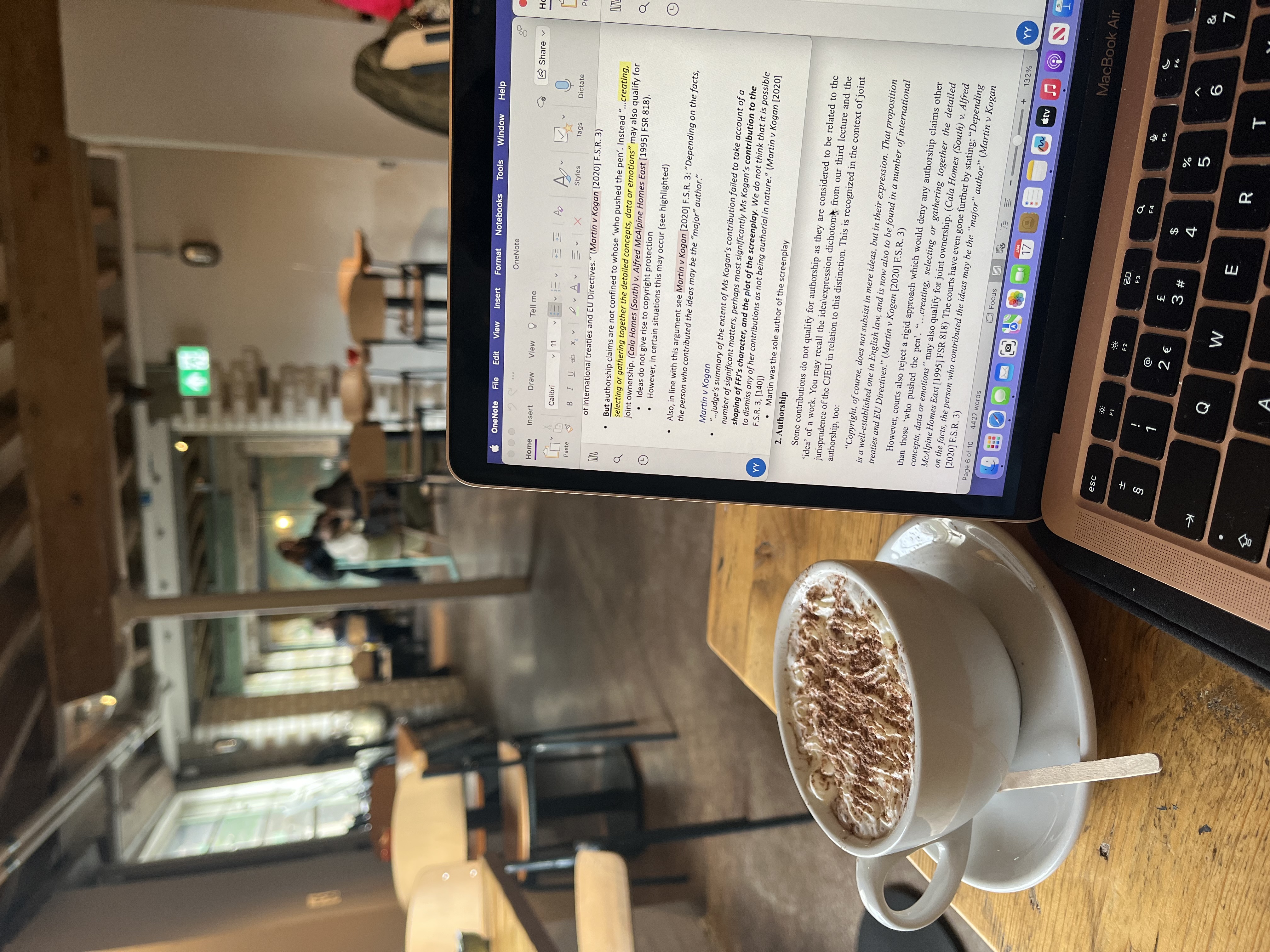 A cappuccino and laptop on top of a  coffee table.