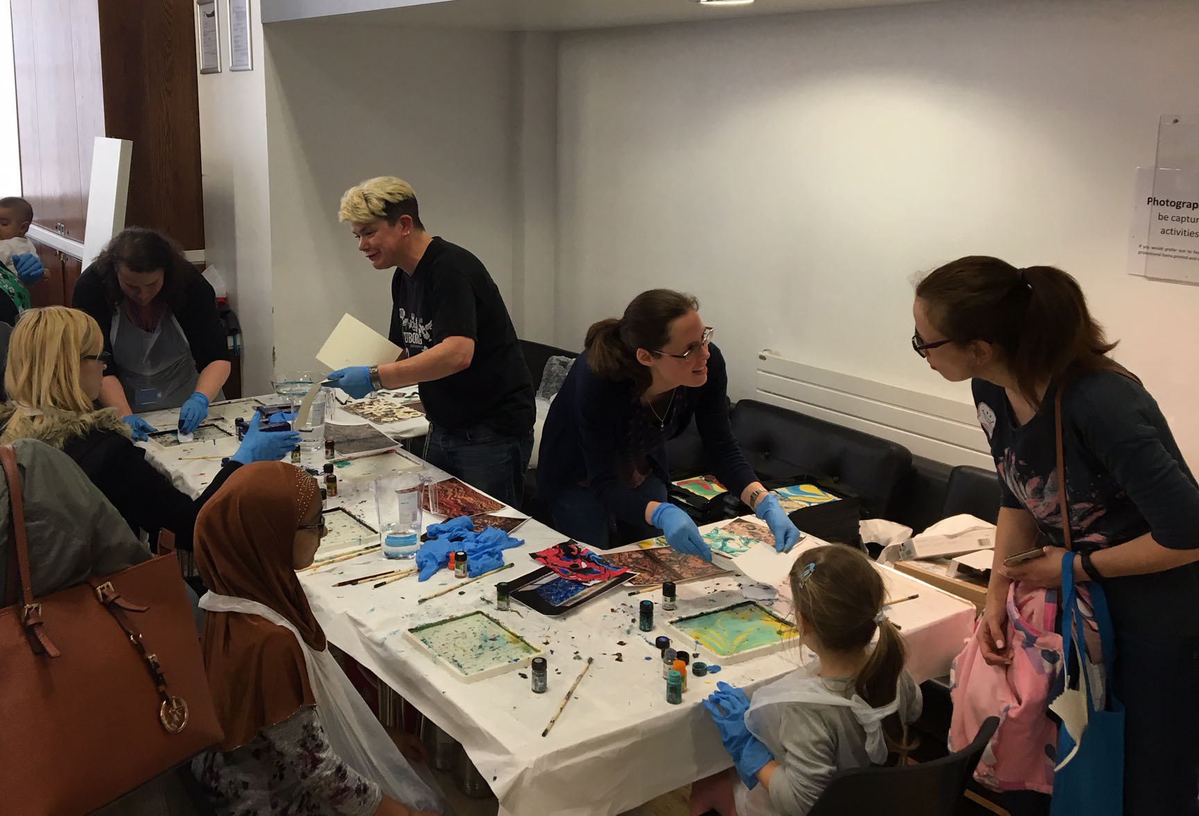 People grouped around a table; there are trays of water and bottles of ink on the table