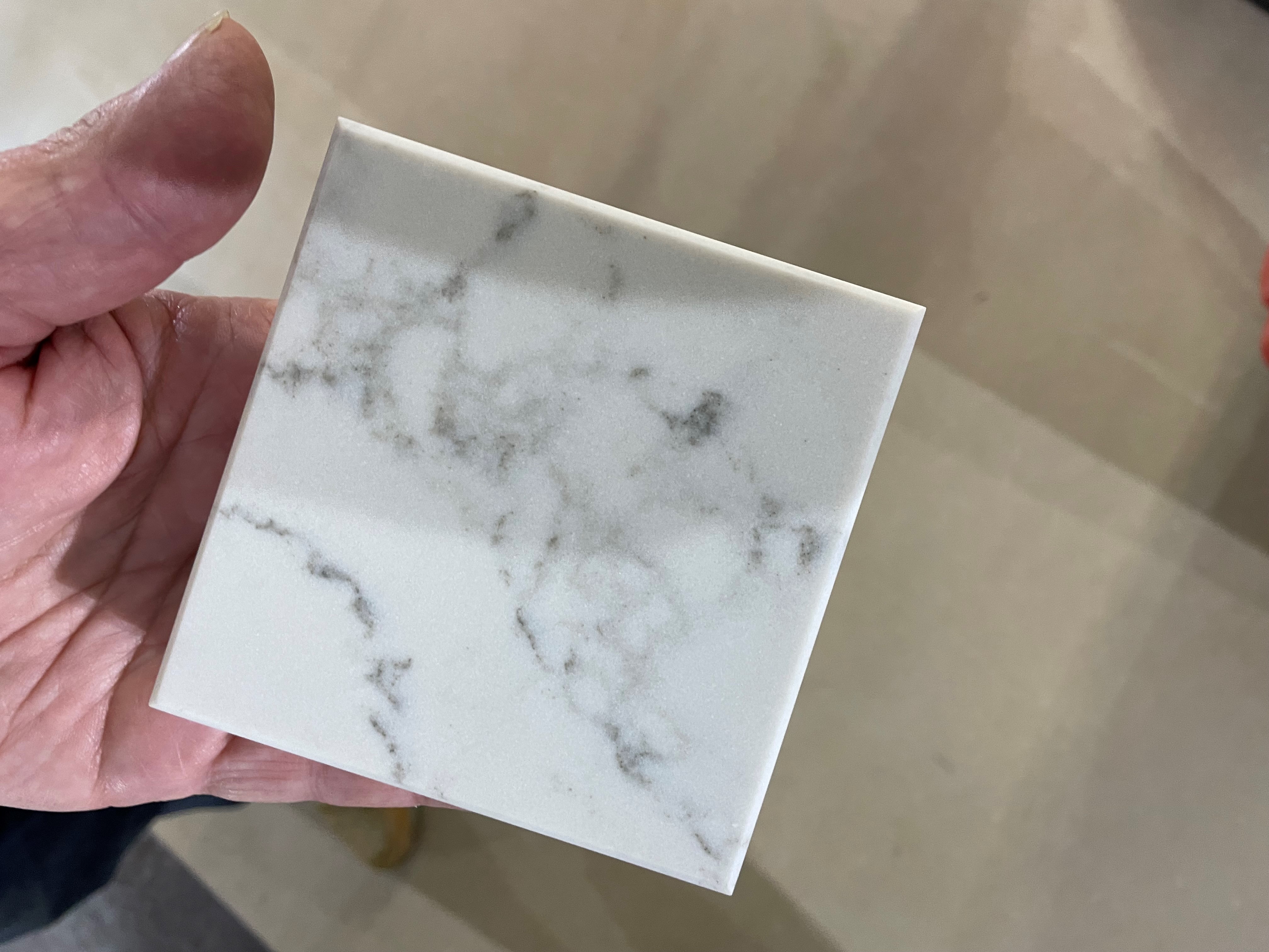 Image showing a sample of white stone with grey swirls in the palm of someone's hand