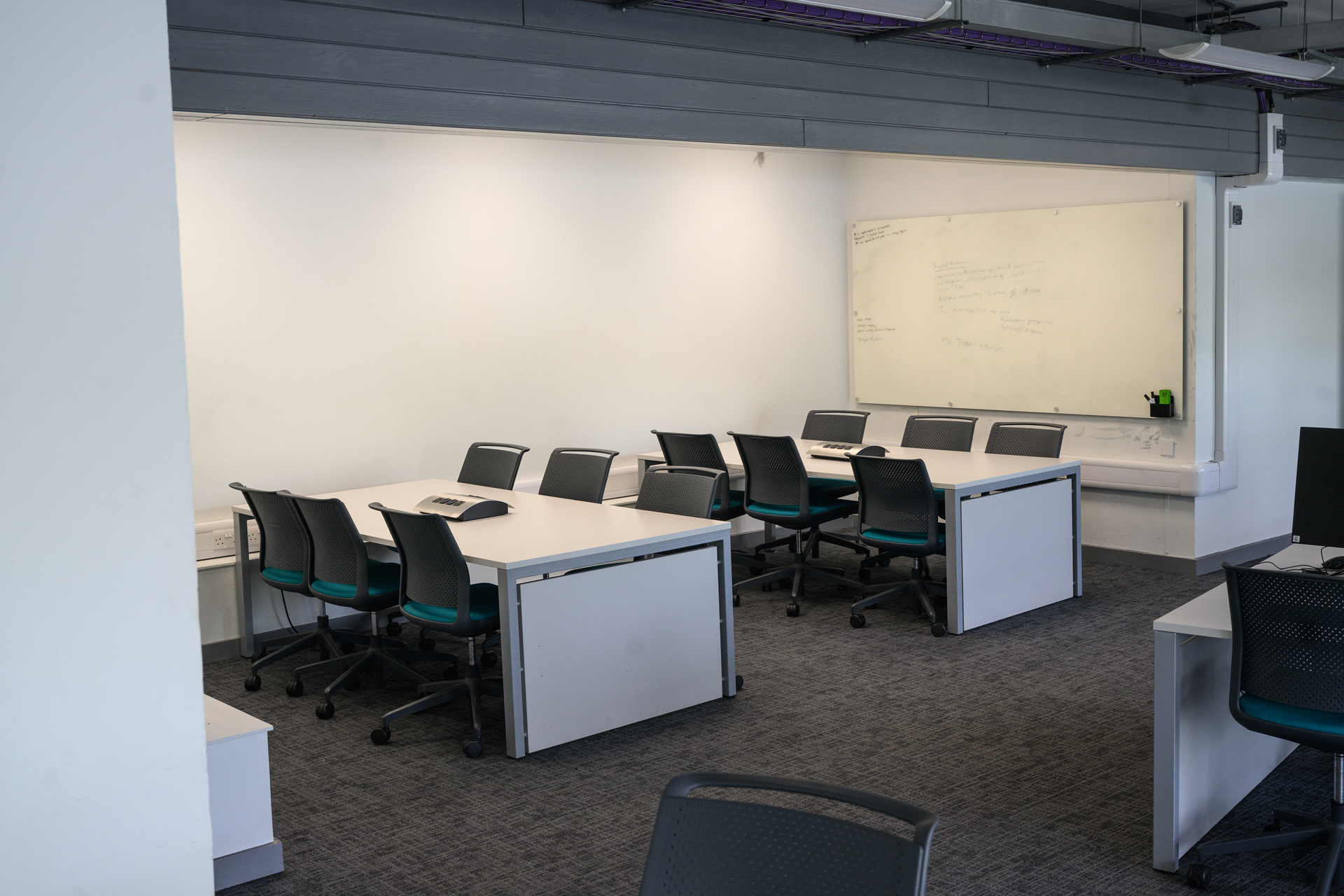 Two sets of empty study desks in front of a whiteboard