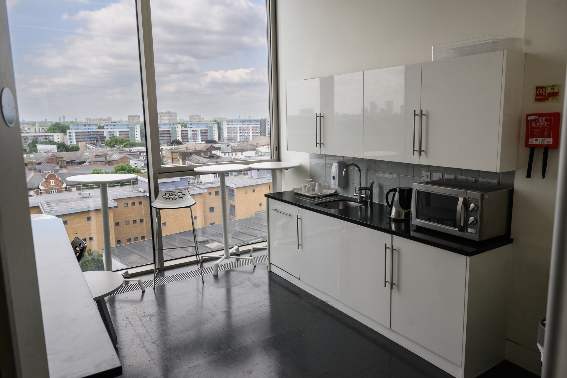 Kitchen with kettle and microwave and bench with bar stools