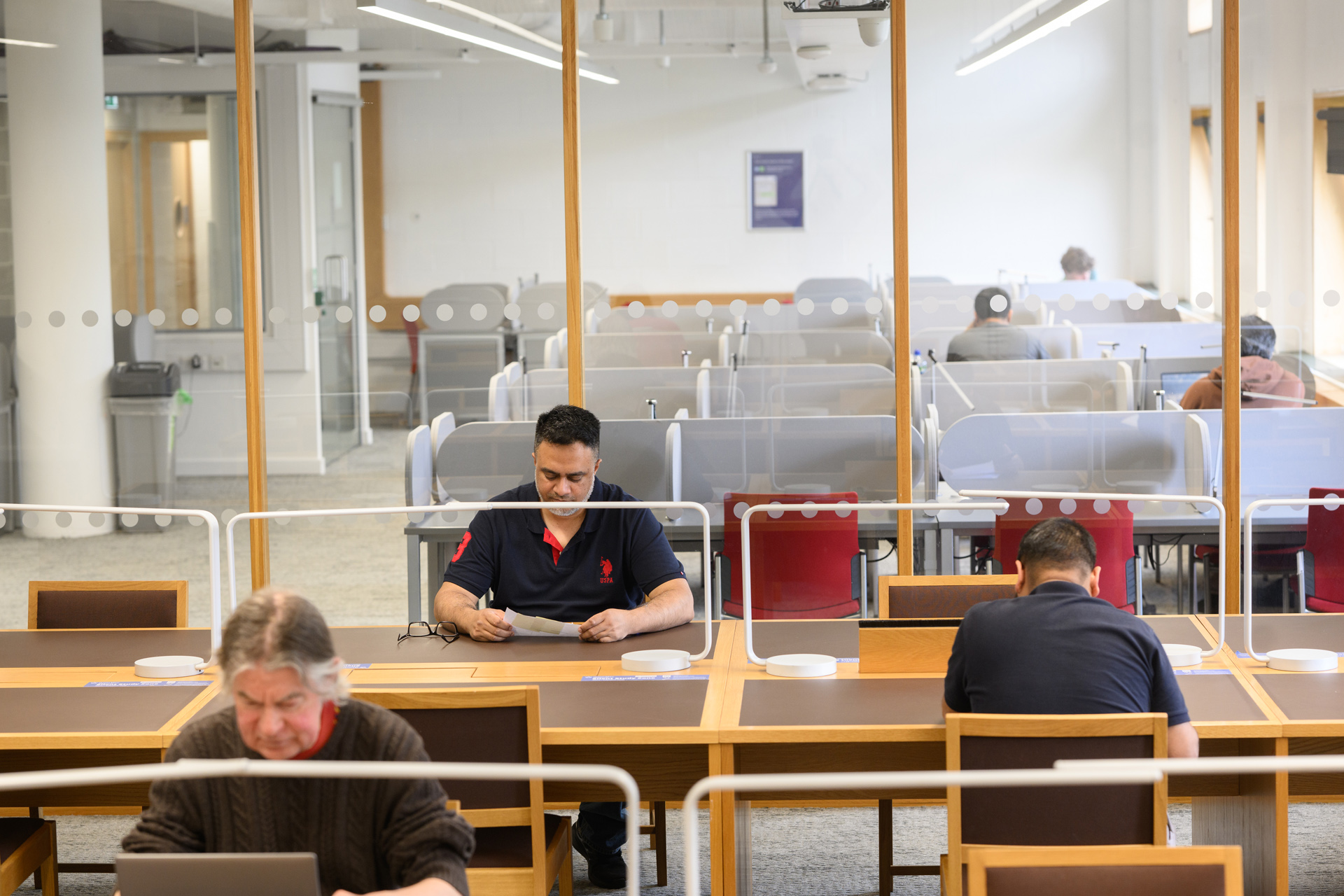 Three postgraduate researchers studying individually