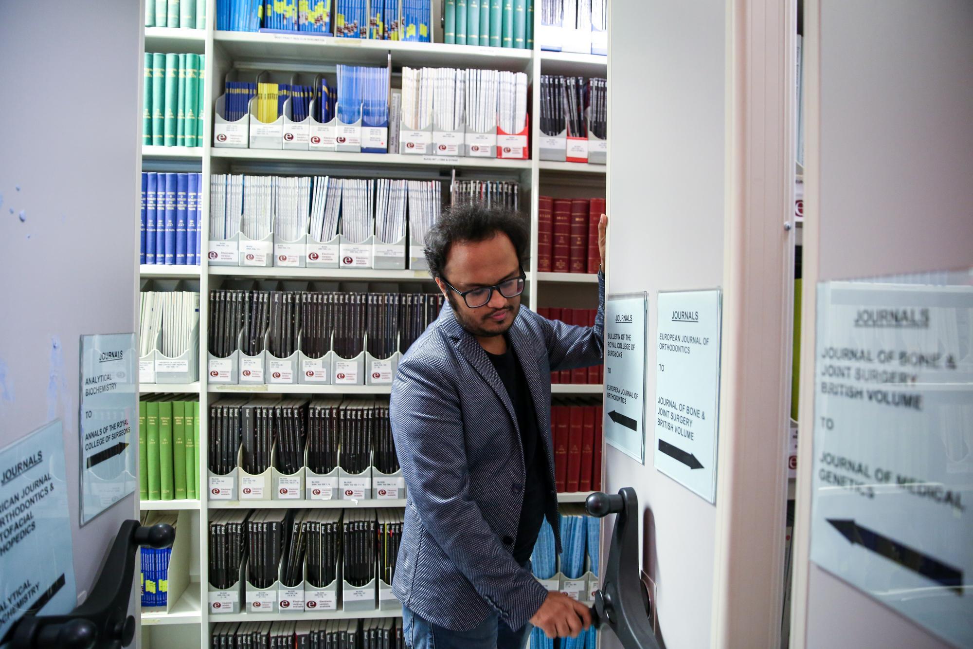 Student turning wheel to move journal shelf stacks