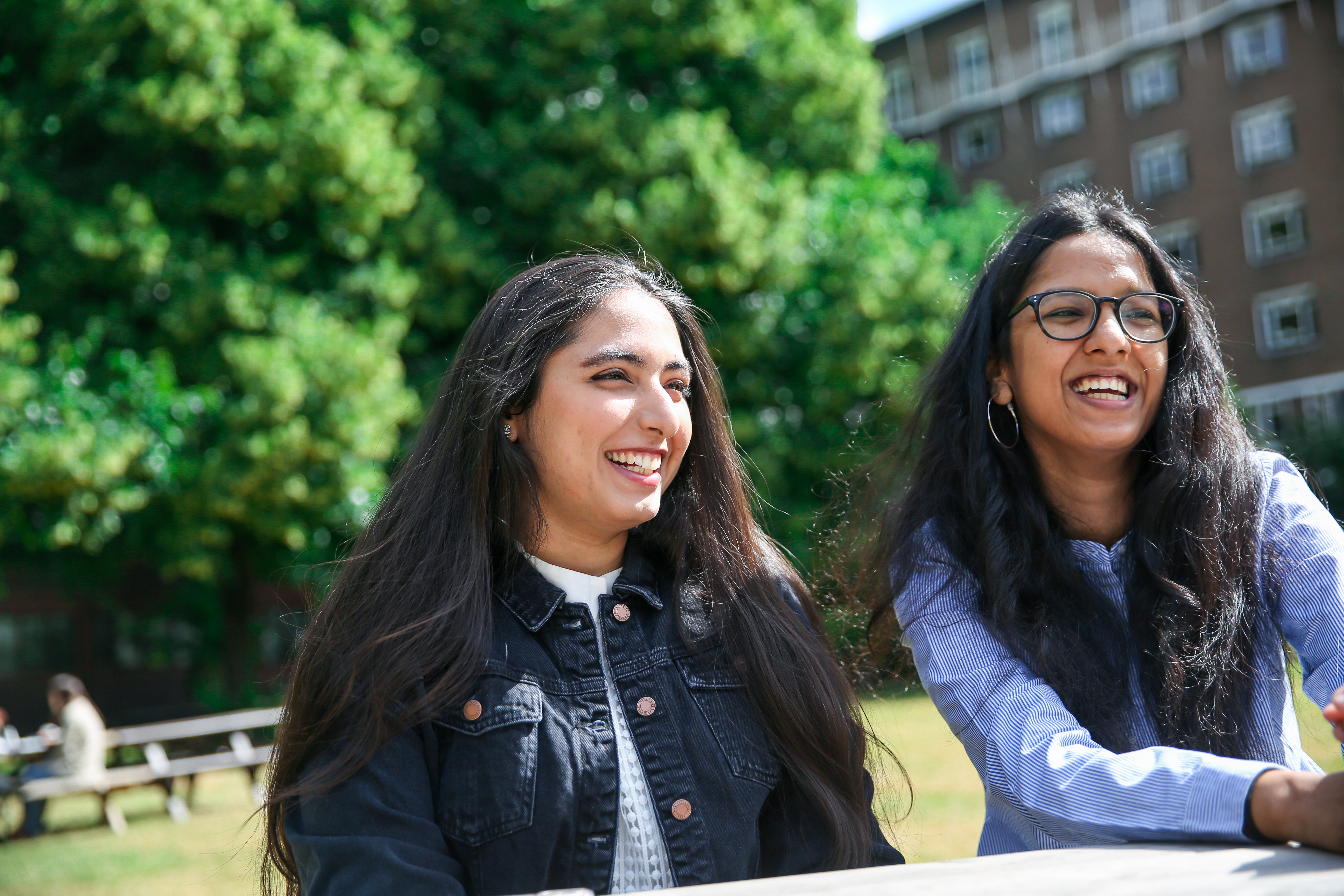 Two students sitting outside smiling