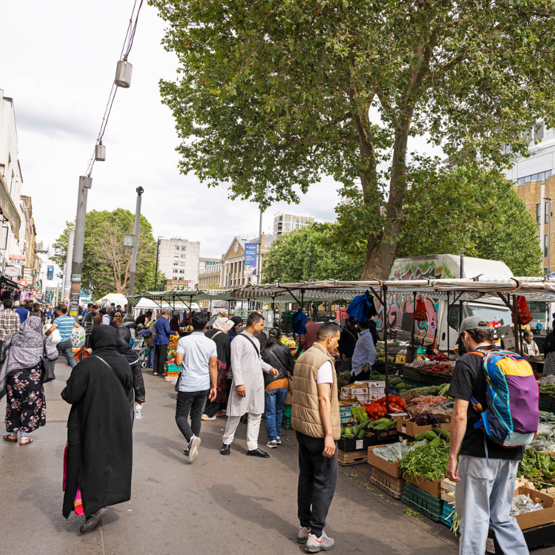 People walk and shop at busy market stalls