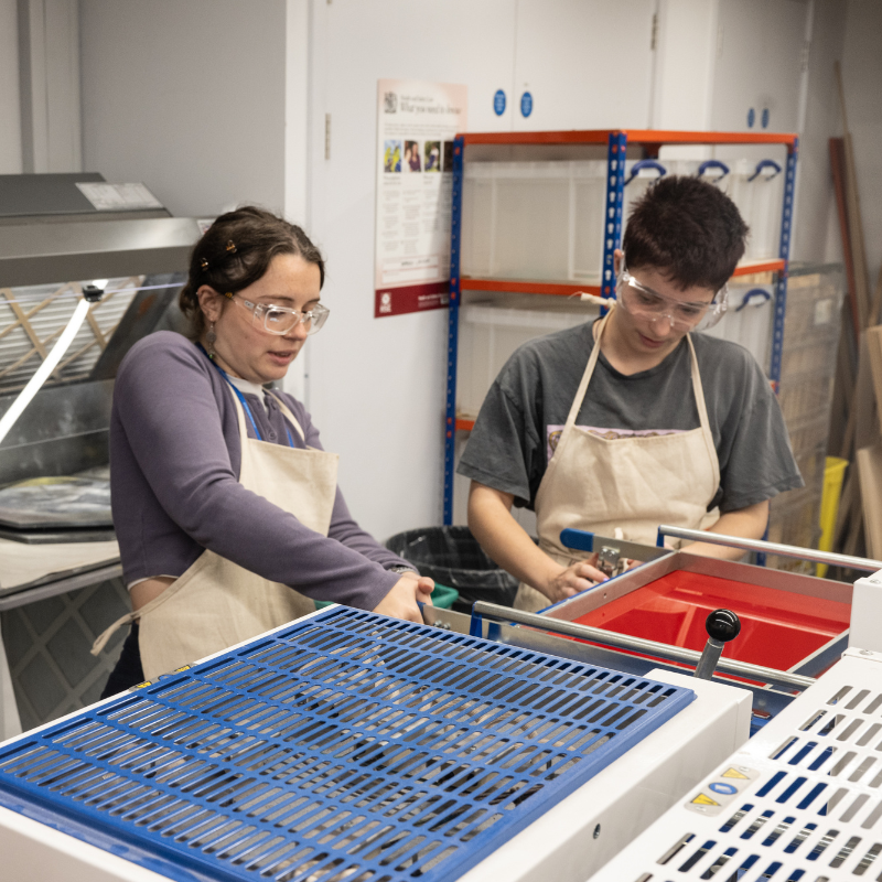 Two students use tools in a workshop