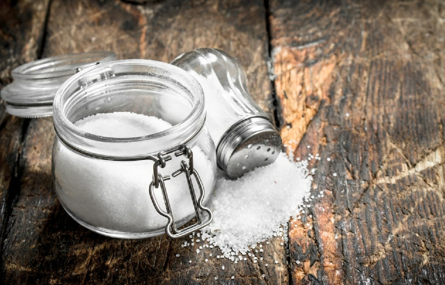 Salt shaker and pot on wooden table.Credit:iStock.com.