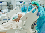 Patient on ventilator lying in hospital bed as medical professional moves his bed. Credit: xavierarnau/iStock.com