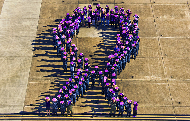 People form a purple ribbon to raise awareness for domestic violence