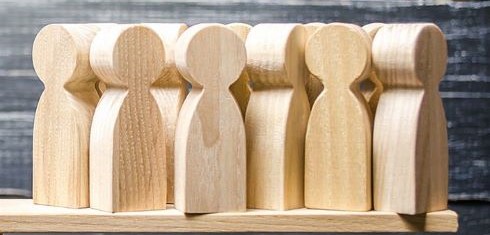 Wooden blocks resembling people lined up on a board