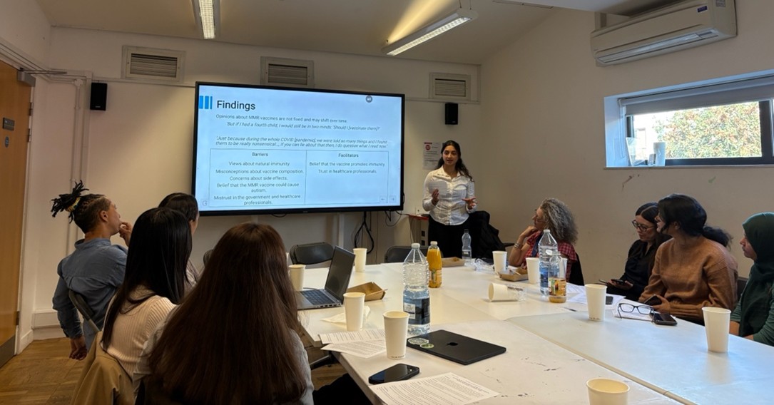 A group of people sitting around tables in front of a presentation