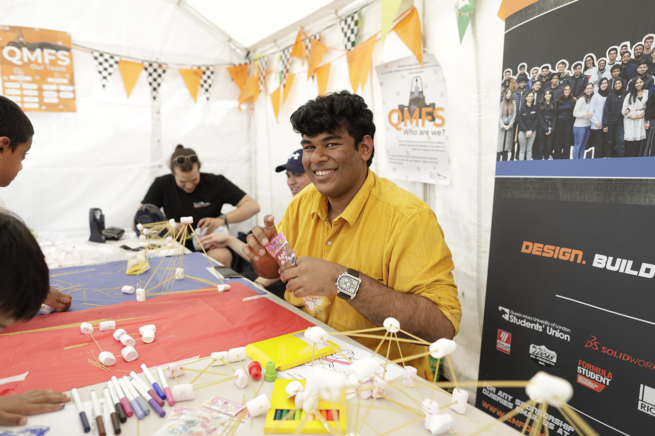A man with dark hair wearing a yellow shirt smiles at the camera