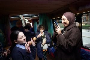 A woman takes a picture of a child holding figurines of planets