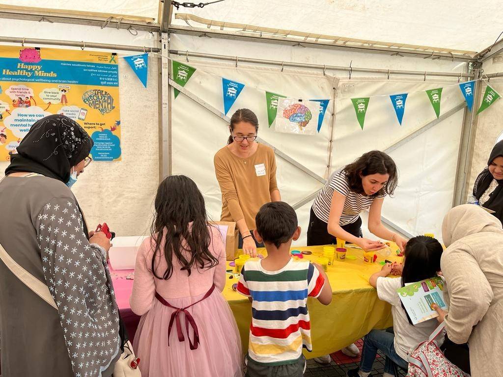 Two people running a festival stall speak to children