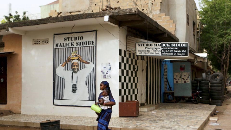 A woman holds her child while walking past the studio of the late, celebrated photographer Malick Sidibé in Bamako, Mali, April 15, 2016