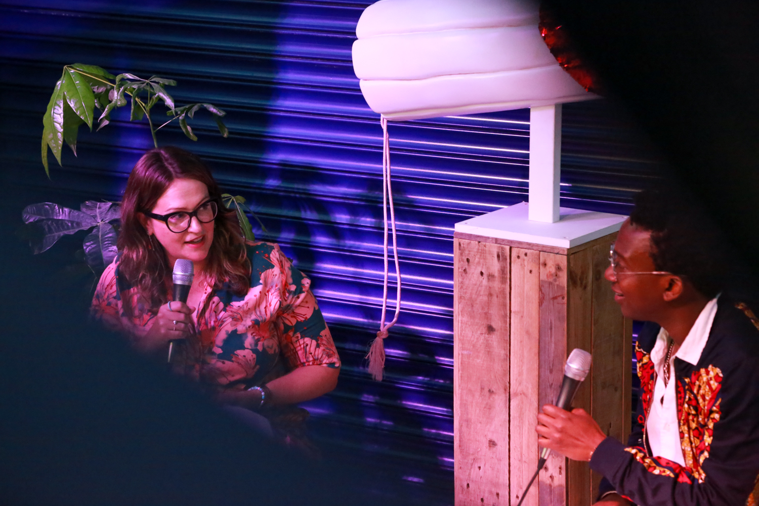 A photo of two people in discussion, both holding microphones.