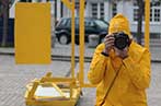 A person wearing a yellow coat taking a photo
