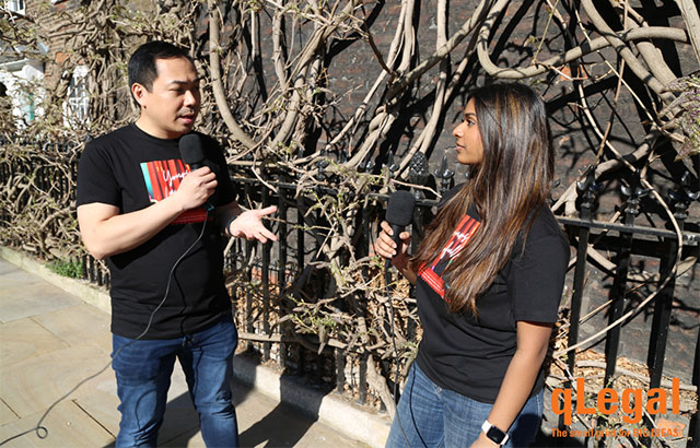 Students holding microphones and recording Yours Lawfully by a Wisteria bush.