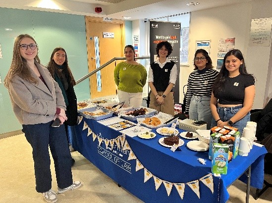 qLegal students standing at a cake stand in the foyer of CCLS.