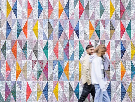 A student standing in front of a colourful mural