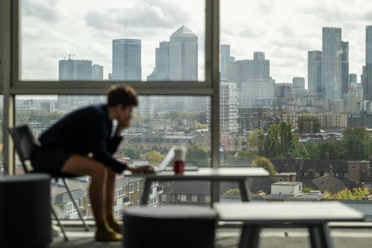Someone working in the Graduate Centre with a view of Canary Wharf in the background