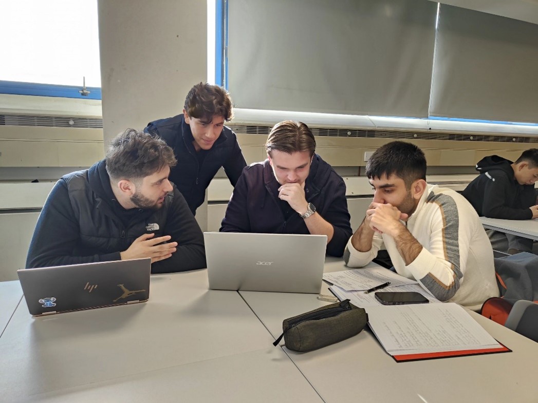 A group of male students sitting around a laptop