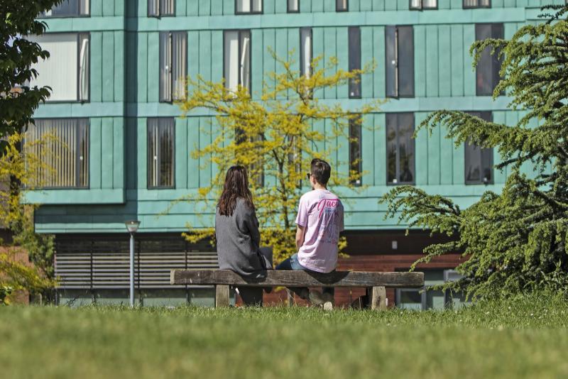 Students sitting on a bench at Mile End campus
