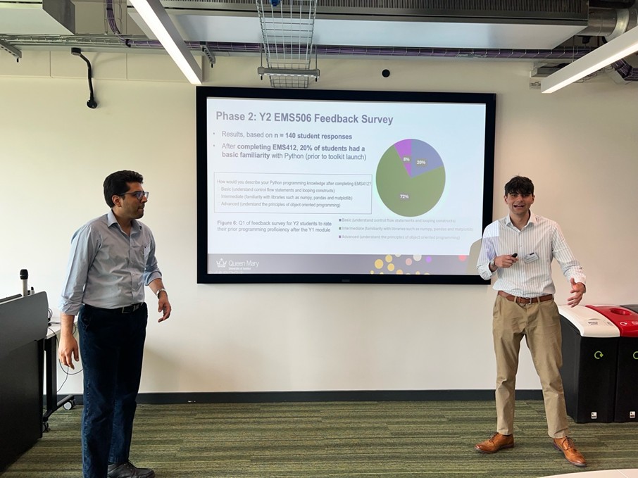 Two speakers presenting in front of a large screen