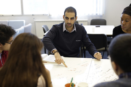 Five people sitting round a table, one is presenting