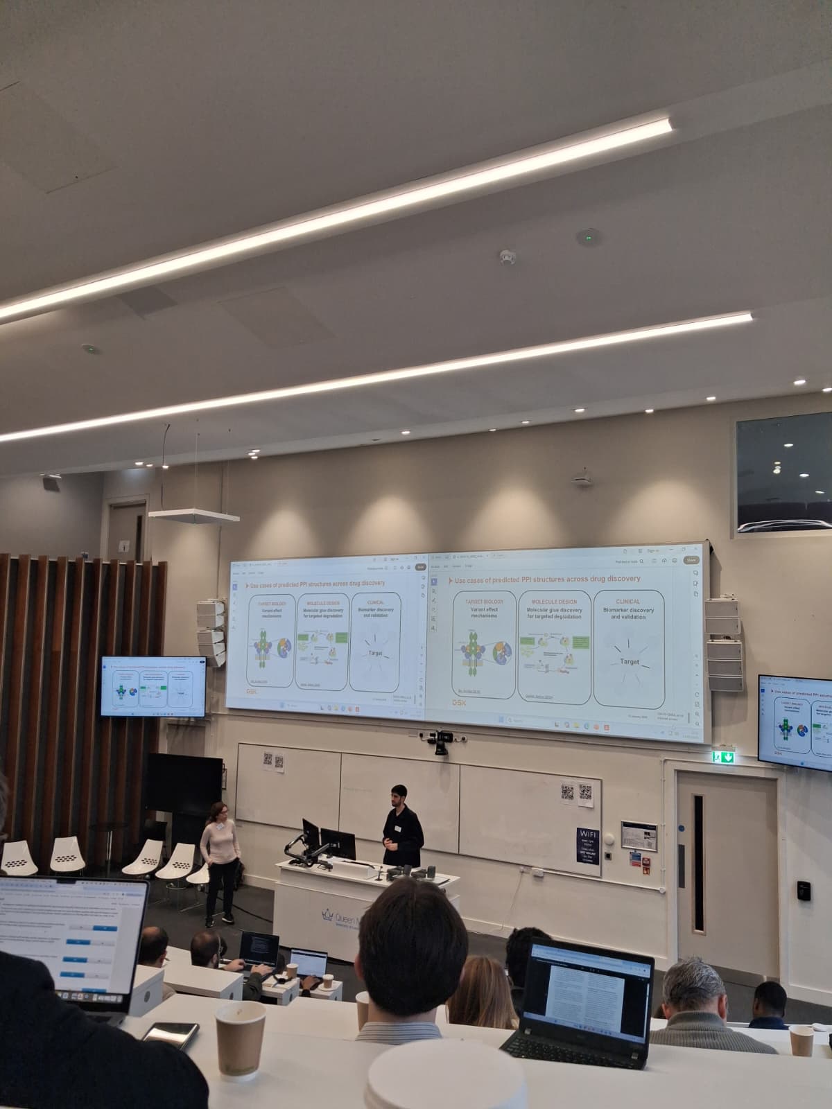 A  screen in a lecture theatre showing molecule work being presented by a lecturer