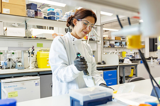 Woman pipetting liquid wearing white lab coat