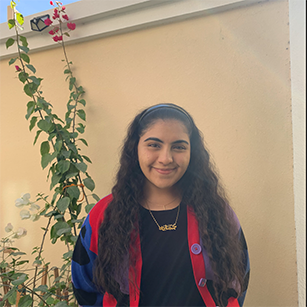 smiling girl standing by wall with flowers