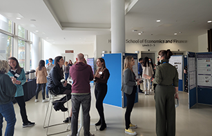 Group of staff and students chatting around posters