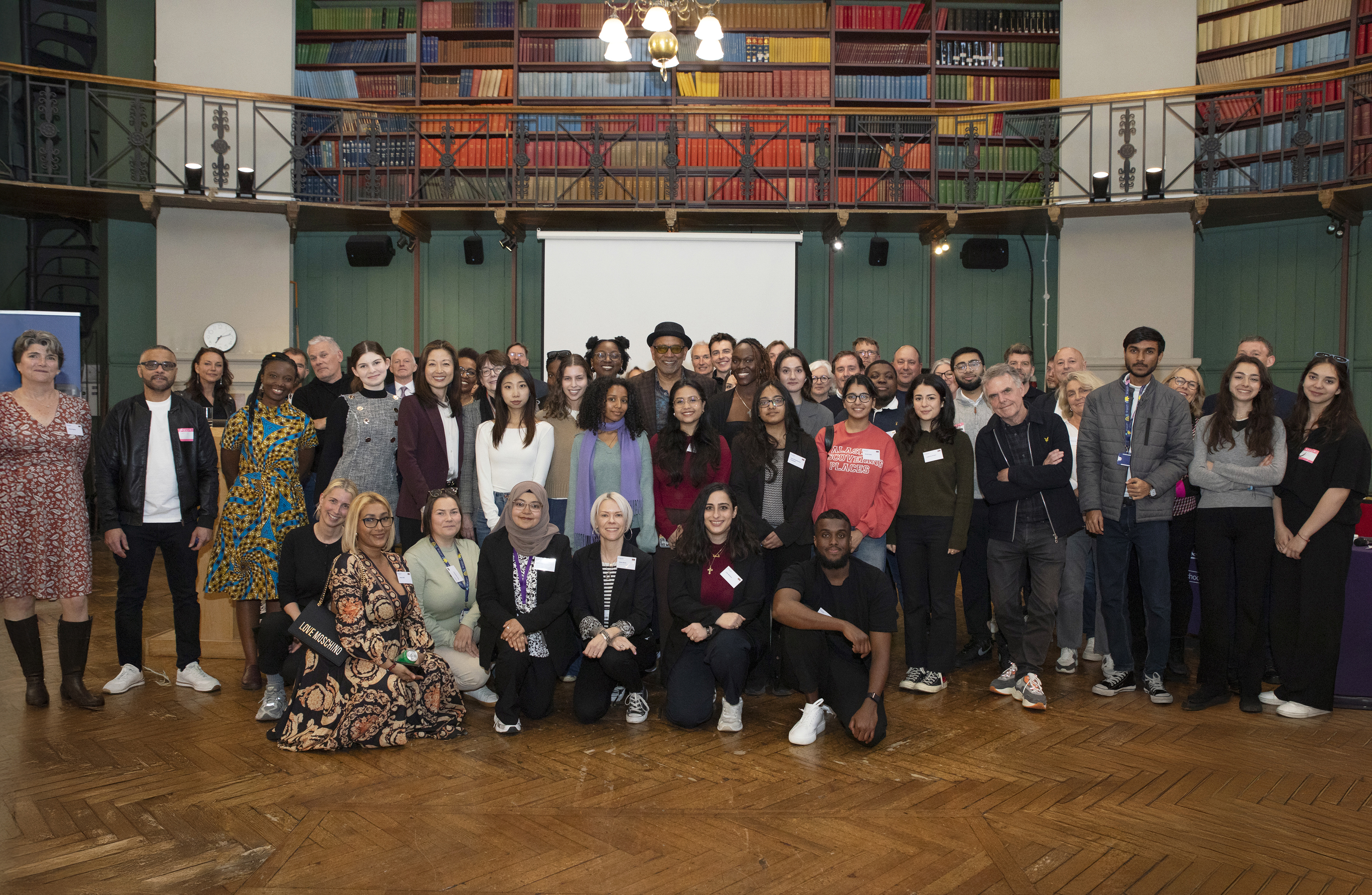 Image of a large group of people standing posing for photo in a traditional hall with books