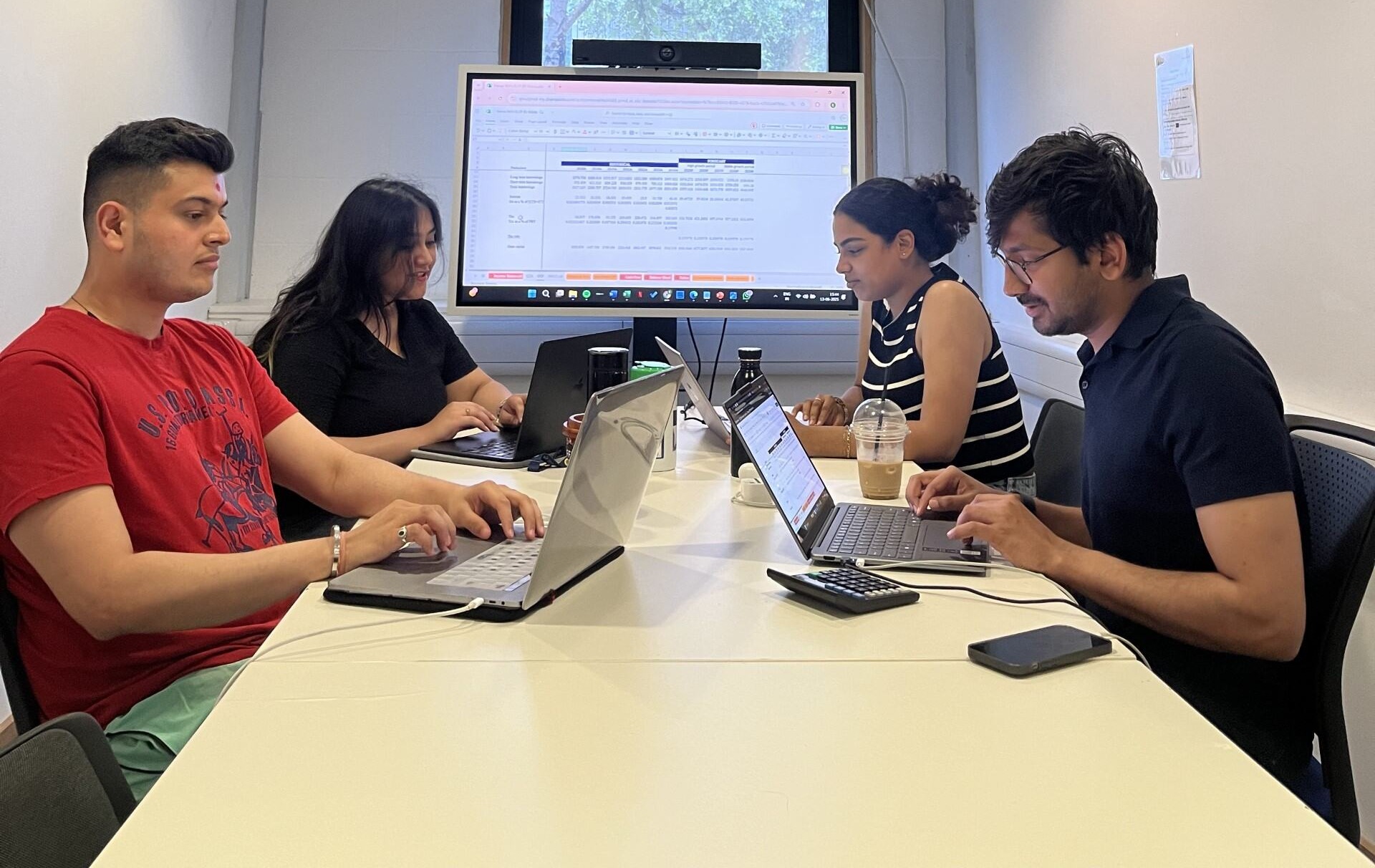 Elvia's QUMMIF team sitting around a table collaboratively working on their project