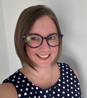 Photo of Karen Hudson smiling to camera with a black top with white dots.