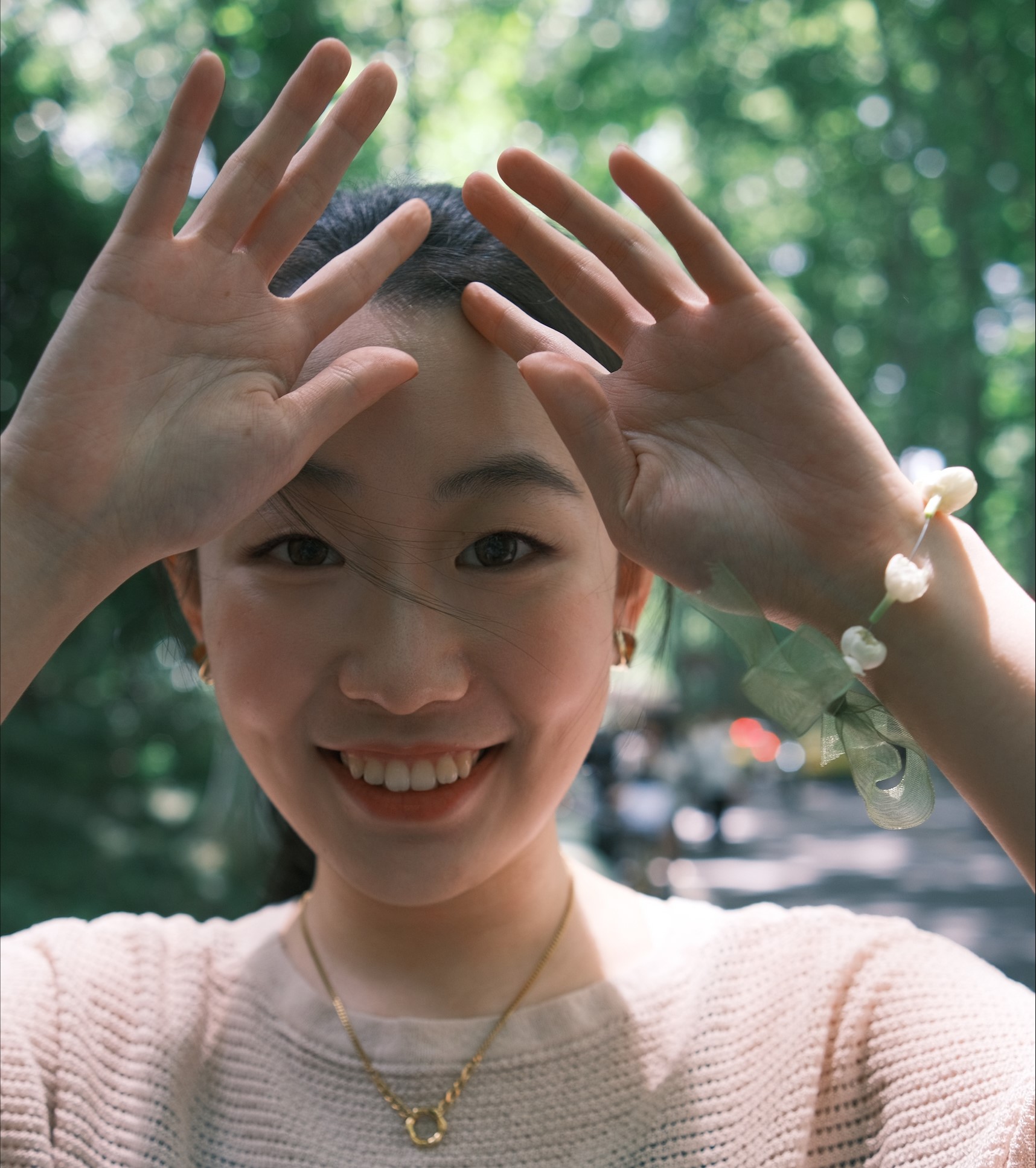 Photo of Xiaoyang Tong, student ambassador with their hands raised and smiling at camera