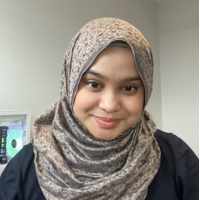 Anis Faqiehah looking at the camera smiling. There is a white wall behind them.