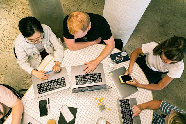 Several people at a table working together on laptops